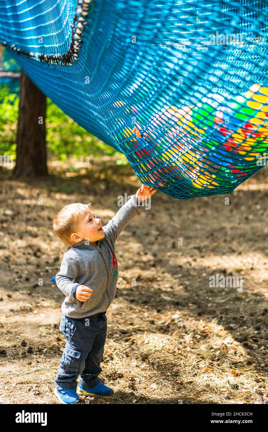 Cute little Polish boy reaching to a net with plastic balls at the