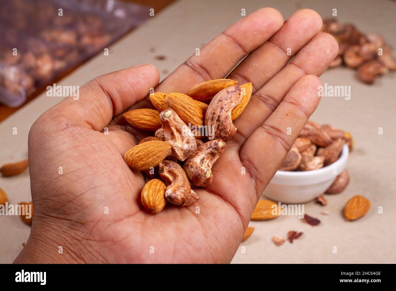 Roasted almond and cashew nuts in hand on light background isolation. Stock Photo