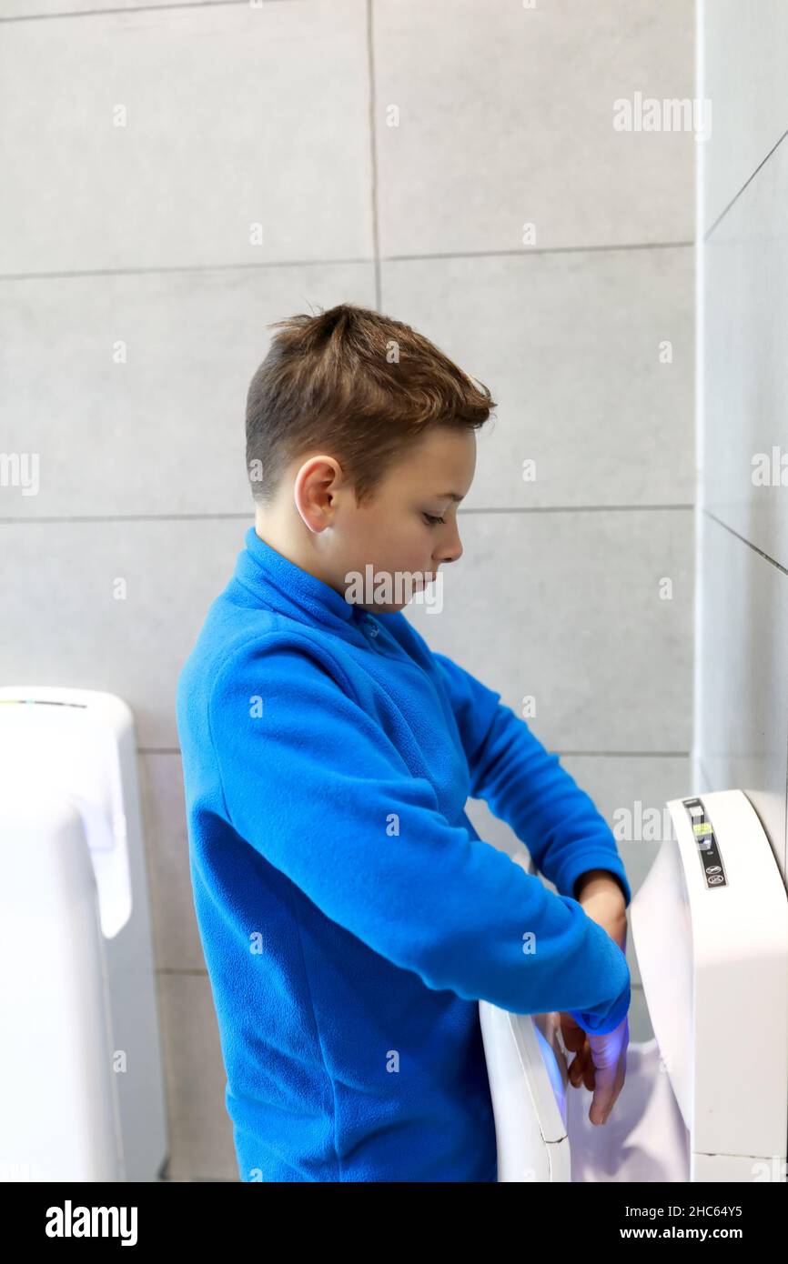Child drying his hands with dryer in restroom Stock Photo Alamy