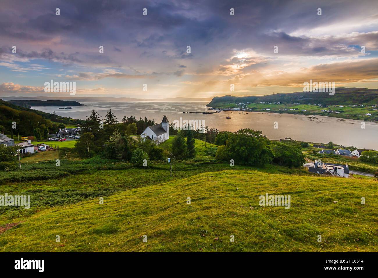 place in Scotland on the Isle of Skye. Church on a hill with green meadow and trees. View over the landscape with sun rays on the horizon. Dramatic cl Stock Photo