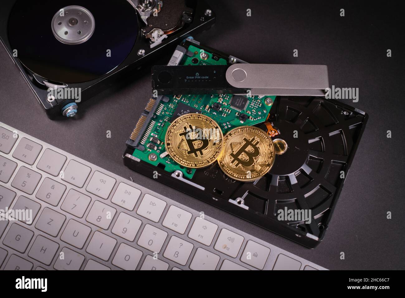 two bitcoin coins are on a hard drive next to a hardware wallet and  keyboard Stock Photo - Alamy