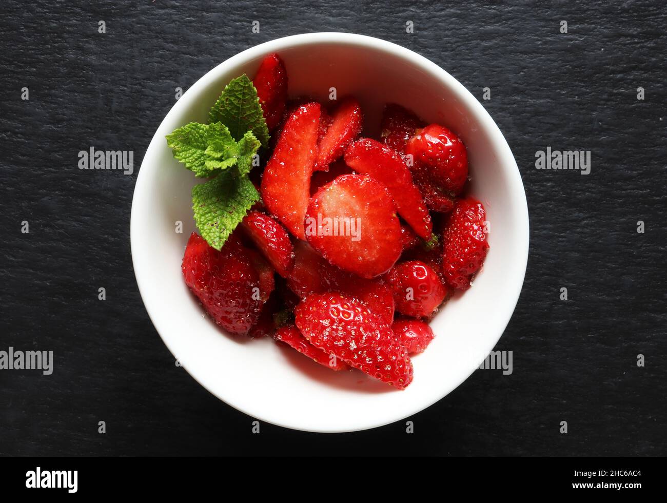 Photography of cut strawberries in ceramic bowl with fresh mint on ...