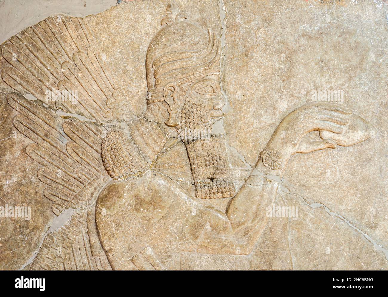 Assyrian wall relief of a winged genius. Ancient carving panel from the Middle East history. Remains of the culture of ancient Assyrian and Sumerian. Stock Photo