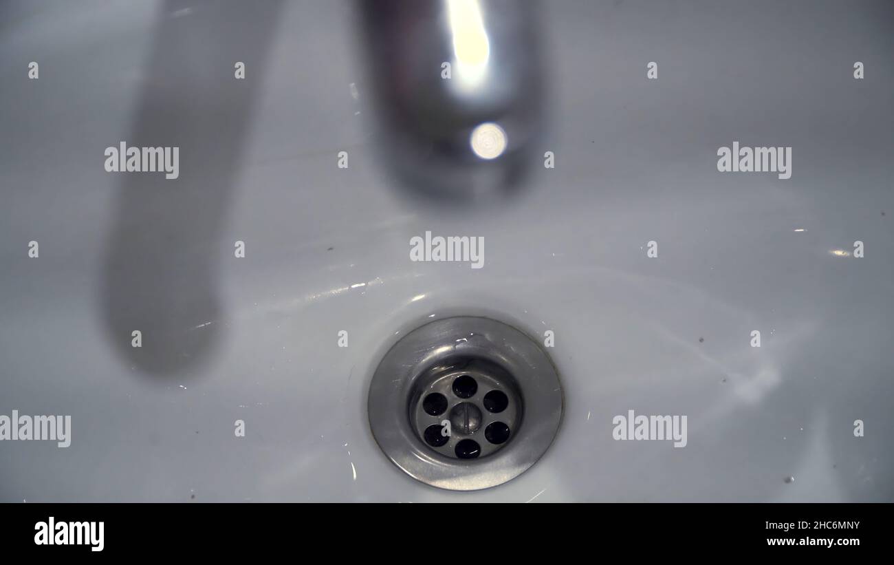 Water flowing from tap into sink. Water dripping from a tap into a sink