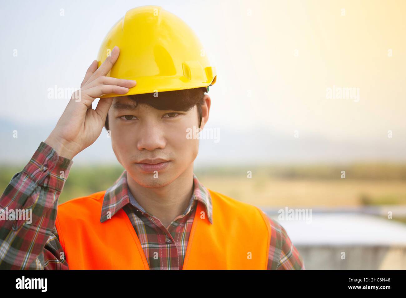 Front view of a young Asian engineer wearing reflective Orange clothing looks serious and happy. He standing on the construction project.And copy spac Stock Photo