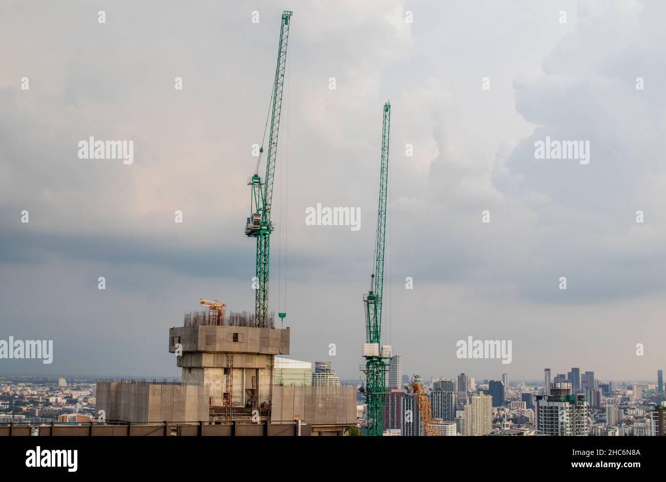 Construction cranes on a roof of a high-rise building against a cloudy sky Stock Photo