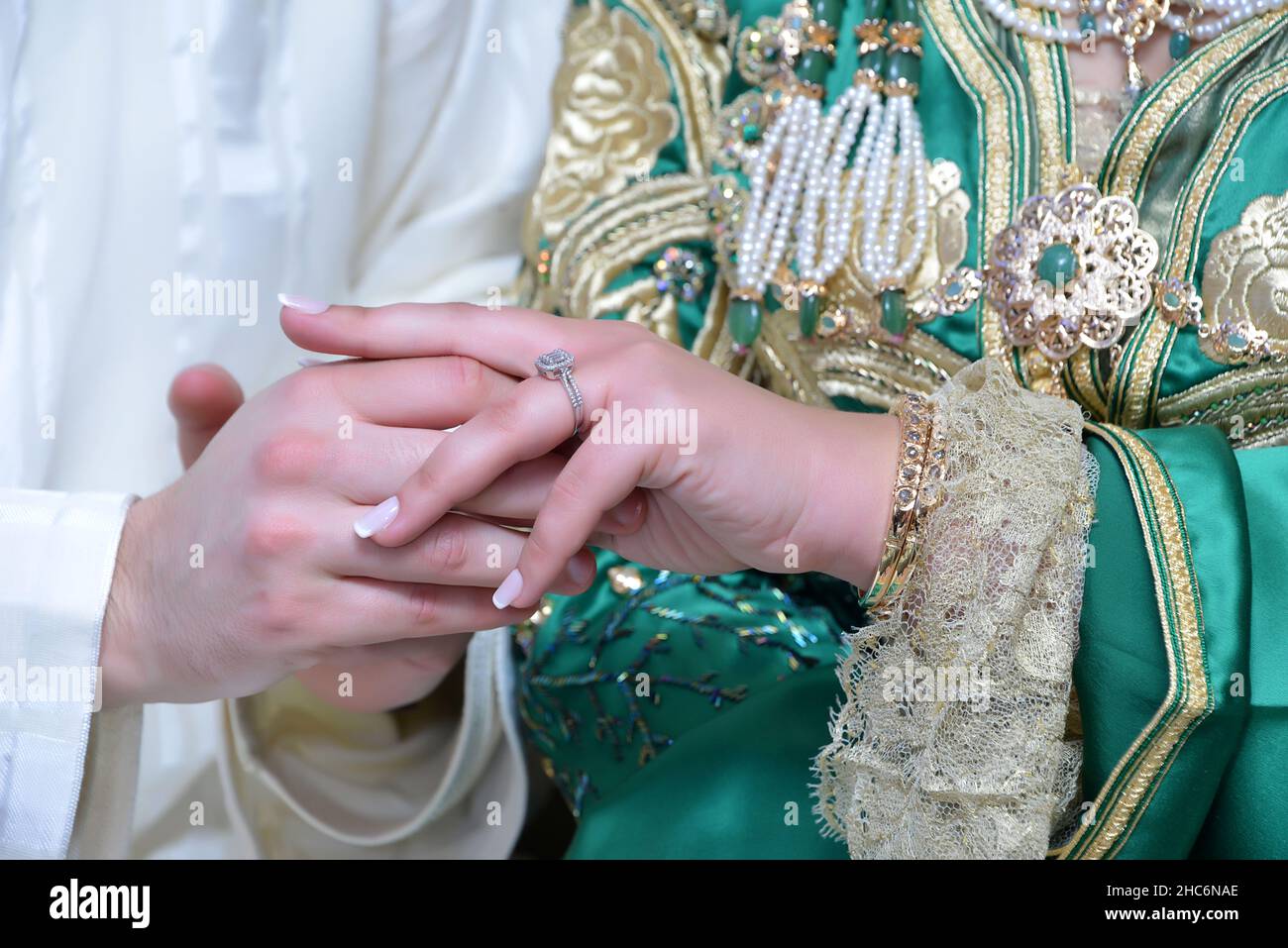 Moroccan groom wears the bride's wedding ring. Moroccan bride in green Moroccan caftan Stock Photo