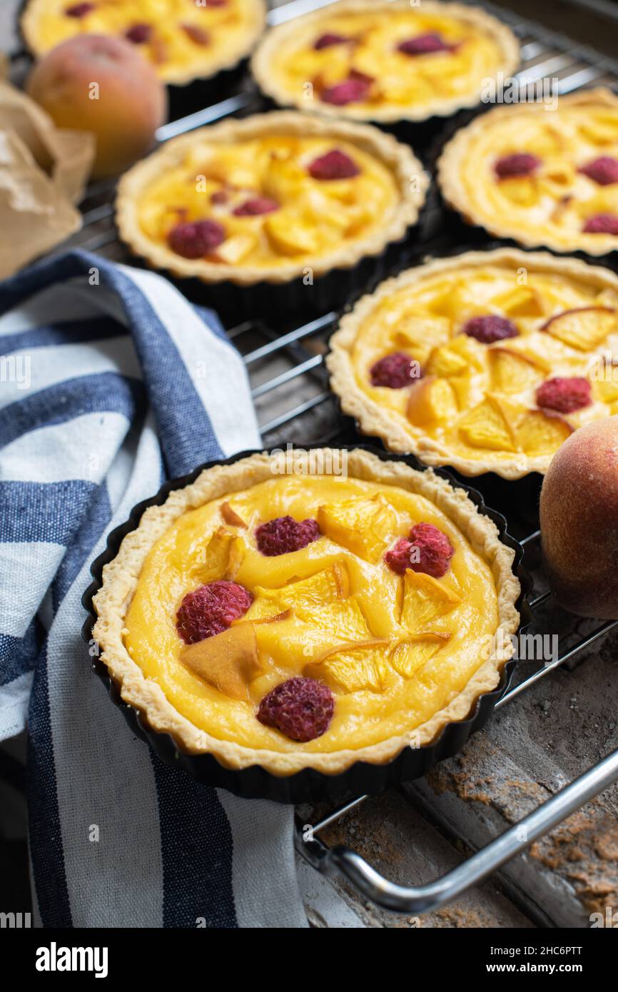 Baked custard tartlets with raspberries and peaches. Close up. Stock Photo