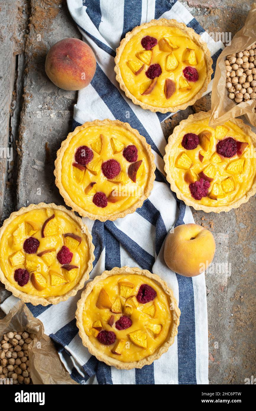 Baked custard tartlets with raspberries and peaches. Close up. Stock Photo