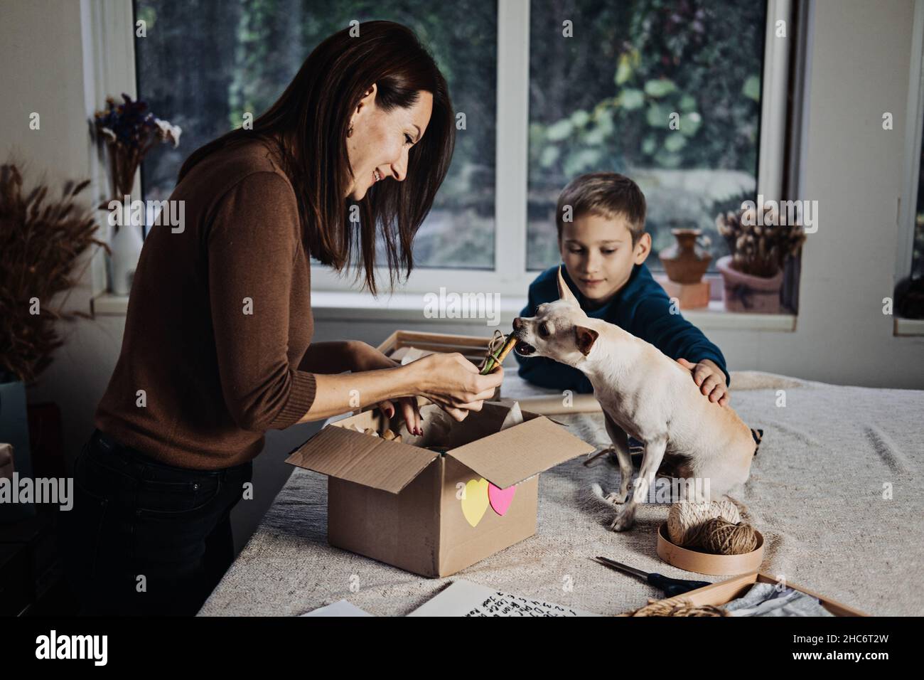 Happy family mom and kid putting bone in Pet Subscription Box for Dogs