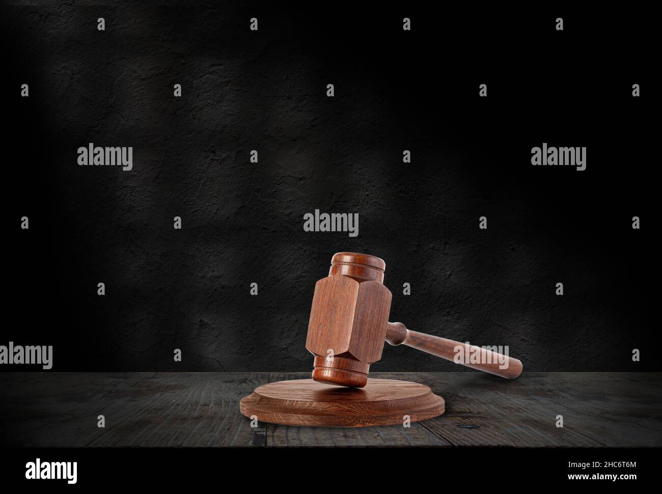 A wooden hammer is a symbol of justice against the dark wall of a prison cell, with copy space Stock Photo