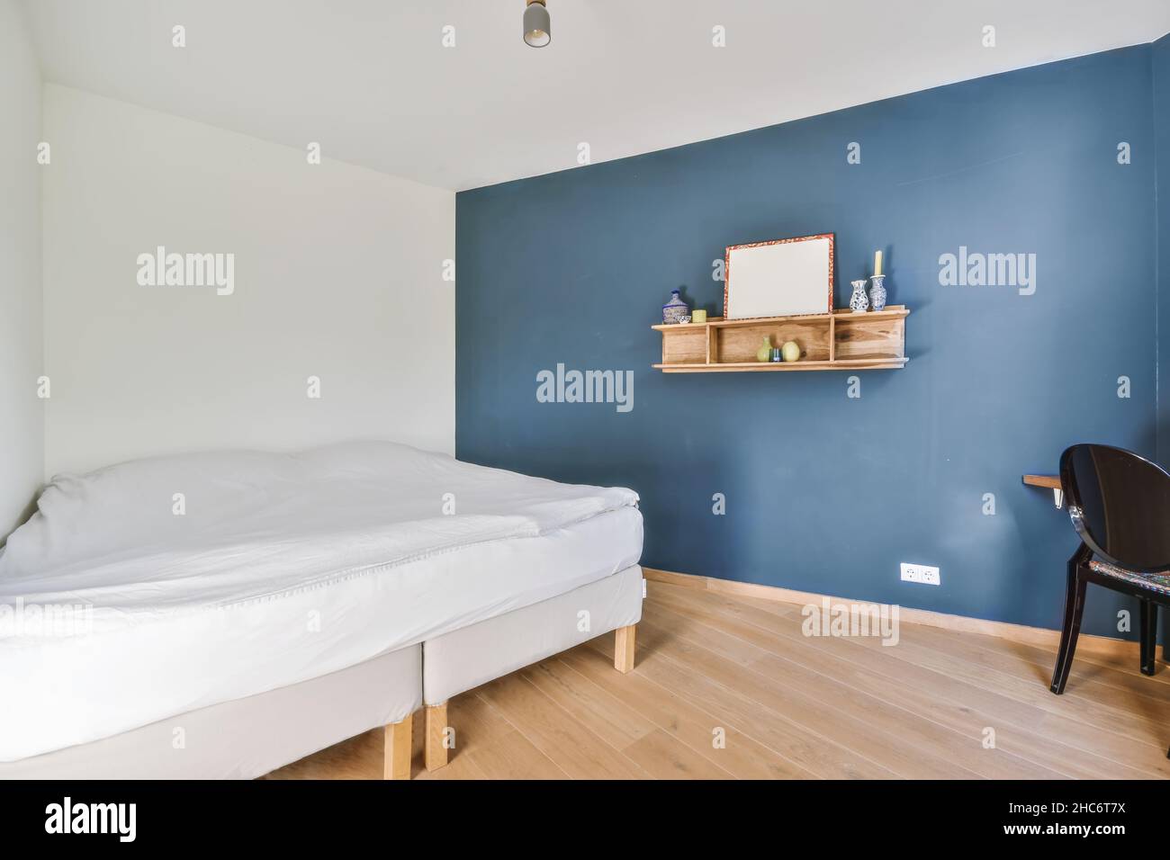 Lovely bedroom with one blue wall and a comfortable bed Stock Photo - Alamy