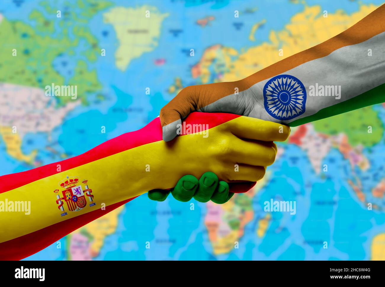Handshake between Spain and India flags painted on hands.With background of world map Stock Photo