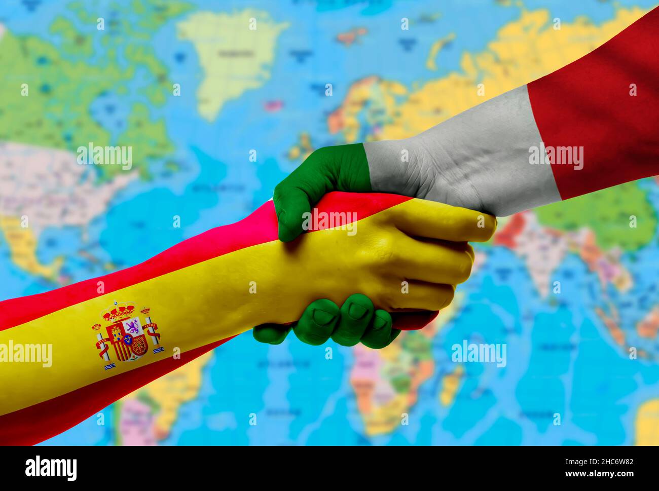 Handshake between Italy and Spain flags painted on hands.With background of world map Stock Photo