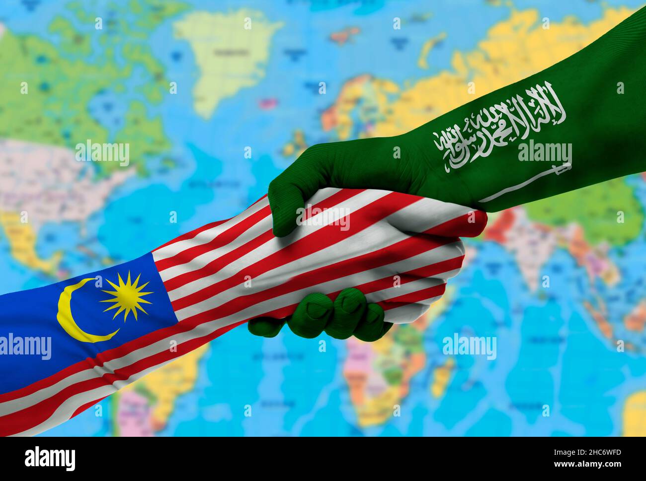 Handshake between Saudi Arabia and Malaysia flags painted on hands.With background of world map Stock Photo