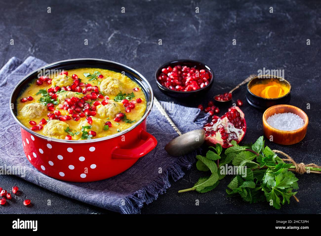 Ashe Anar, Persian Split Pea Pomegranate Soup with lamb Meatballs in a red pot on a concrete