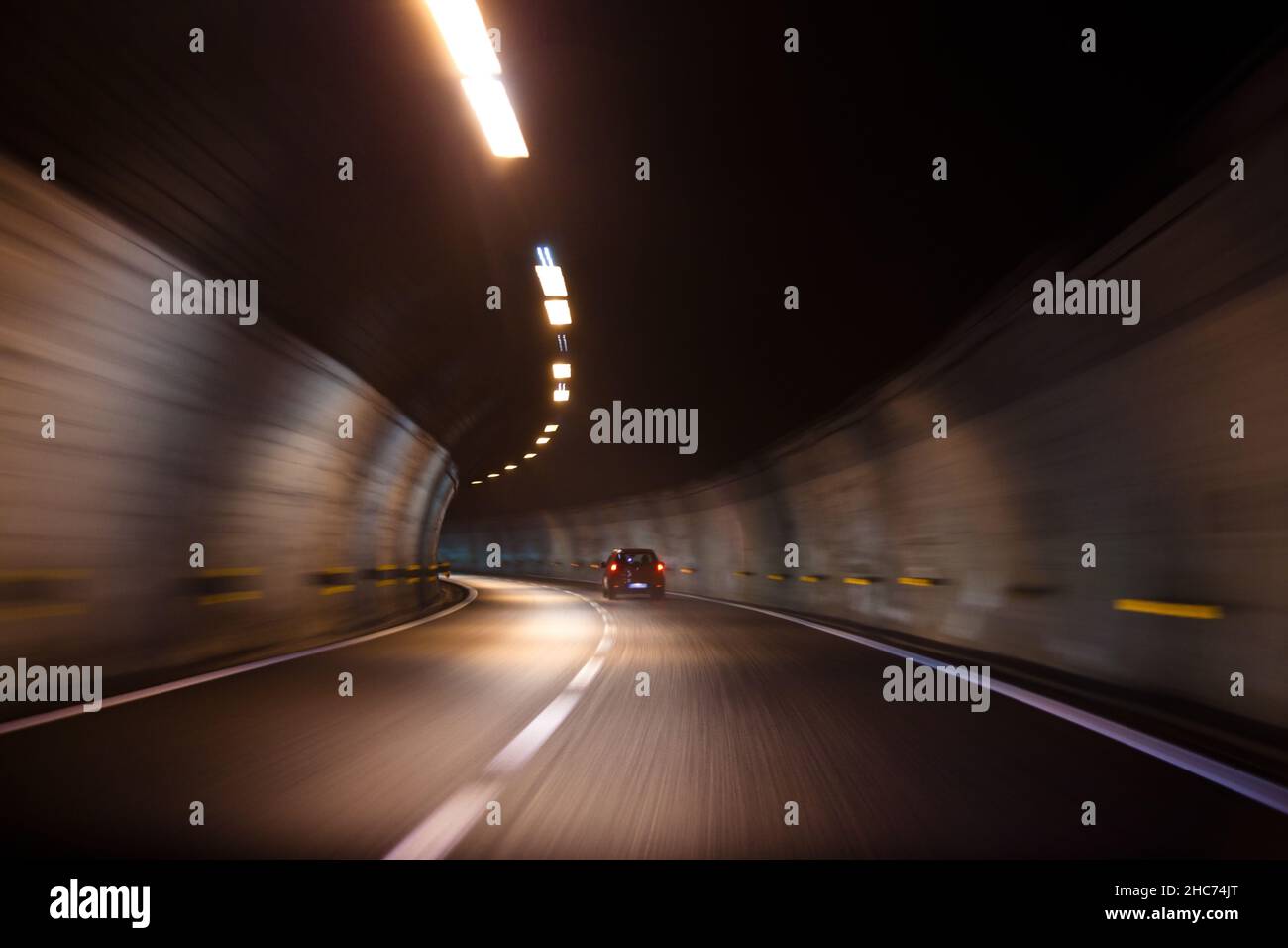 Fast moving car driving in a tunnel with lights and with very good quality of road inside it Stock Photo