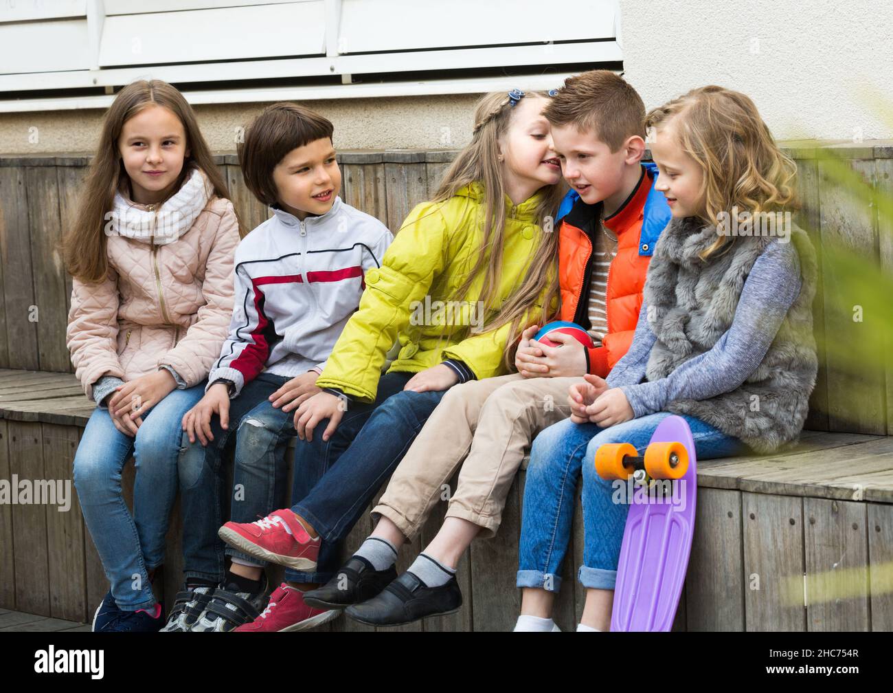 Kids whispering in other ears outdoor. Stock Photo