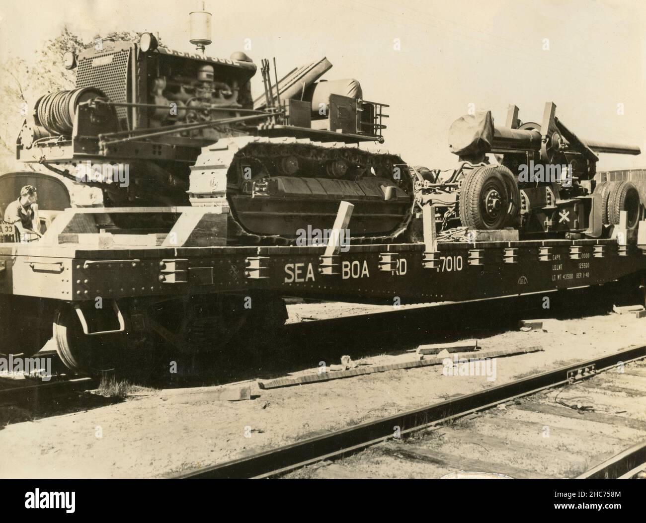 A US Army Caterpillar Tractor  and a 155mm Gun on a single flat car of the US Railroad Transport, USA 1940s Stock Photo