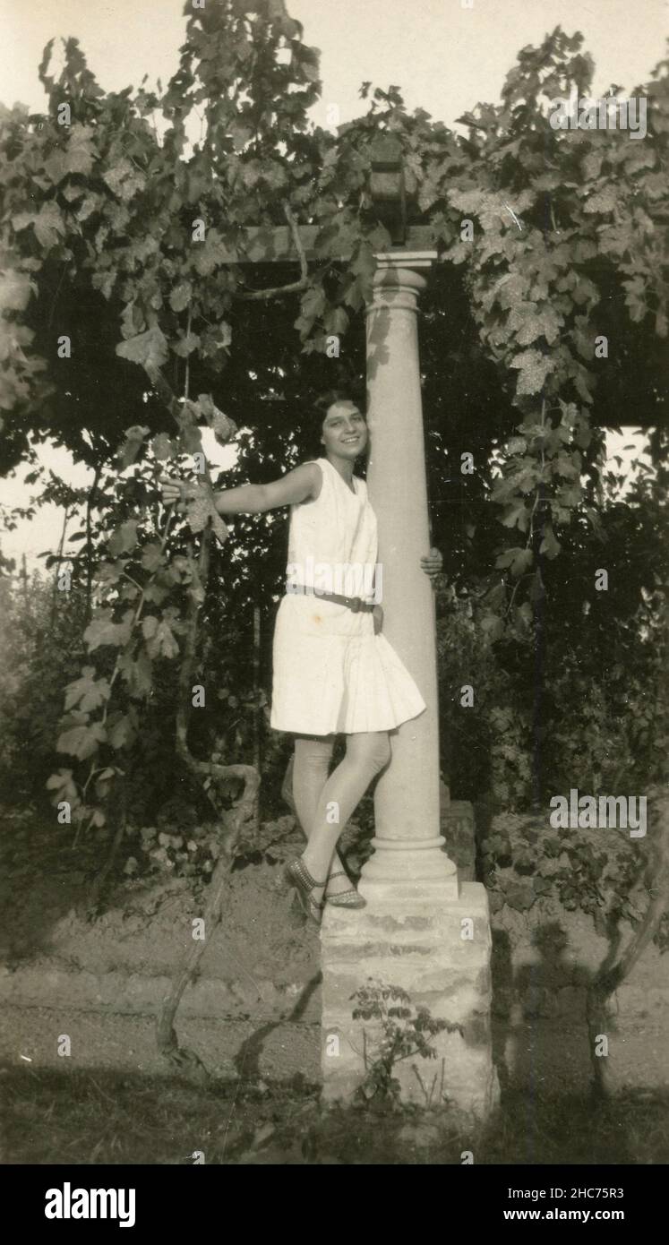 Girl dressed in white in a portico with grapewine, Italy 1920s Stock Photo