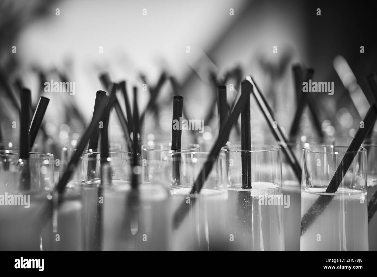 Grayscale selective focus shot of a bunch of drinks with straws at a party Stock Photo