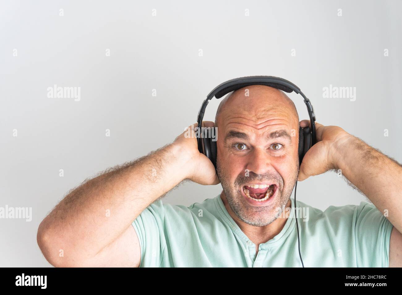 Close-up shot of a face of a bald and bearded Caucasian man, wearing headphones Stock Photo