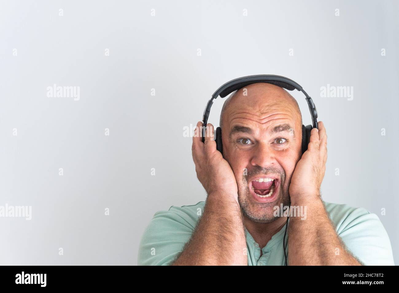 Close-up shot of a face of a bald and bearded Caucasian man, wearing headphones Stock Photo