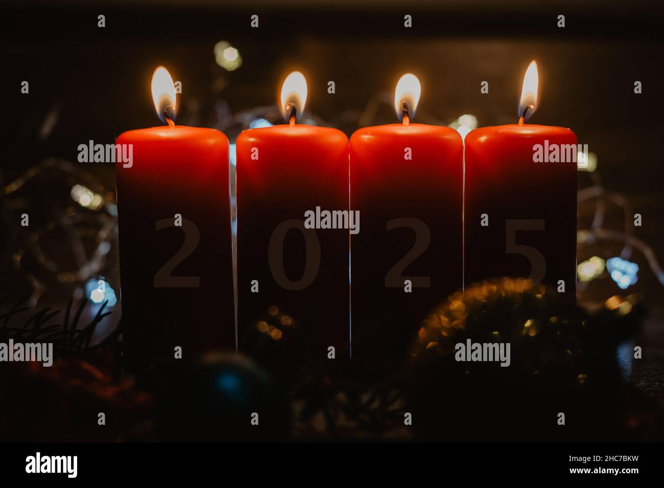 Four red Advent candles with 2025 figures on them and Christmas