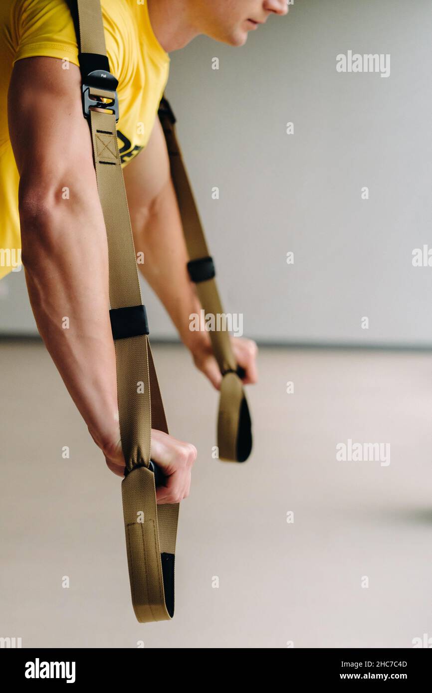 A focused male athlete performing an exercise on functional loops in ...