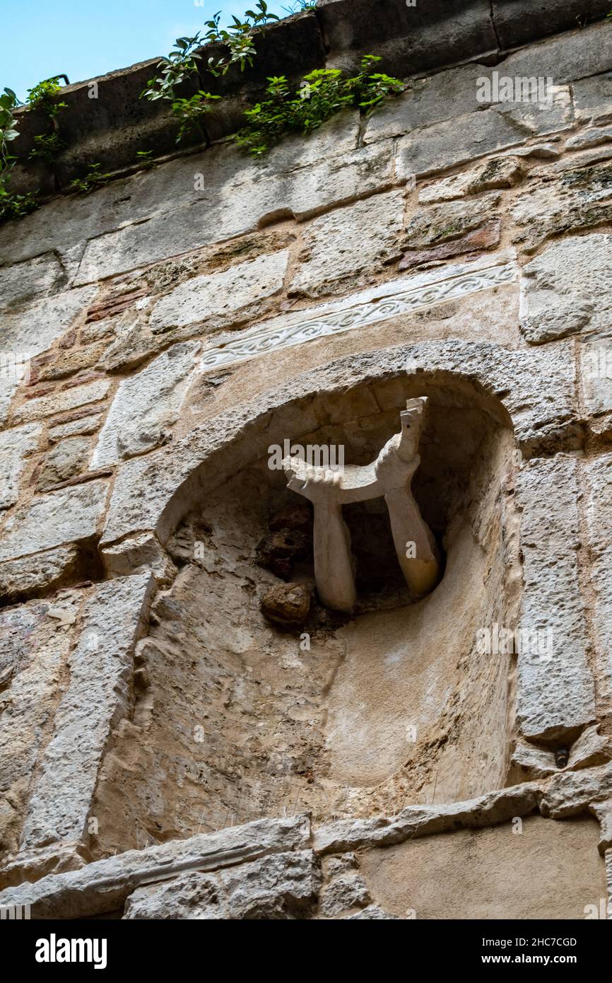 Architecture design, two arms carved in stone thrust out from the side of an ancient building. Artistic detail streets of Croatia, Adriatic Sea city Stock Photo