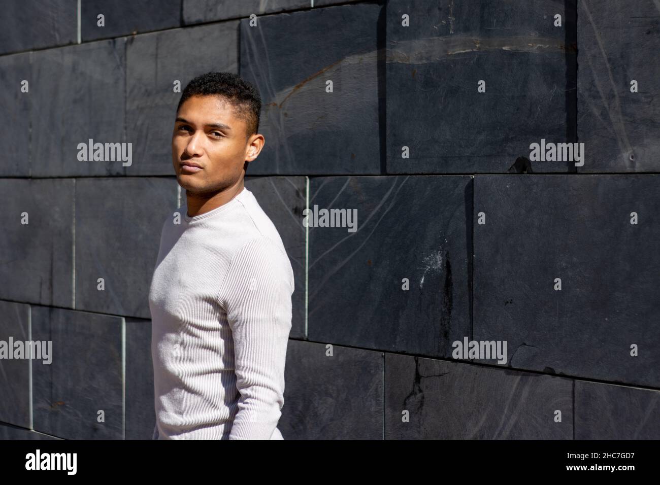 portrait of a young latin guy on a gray wall Stock Photo