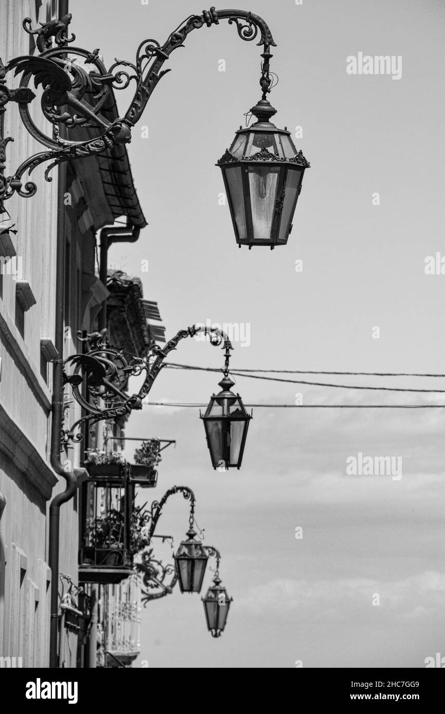 Vertical, grayscale shot of a line of street lamps Stock Photo