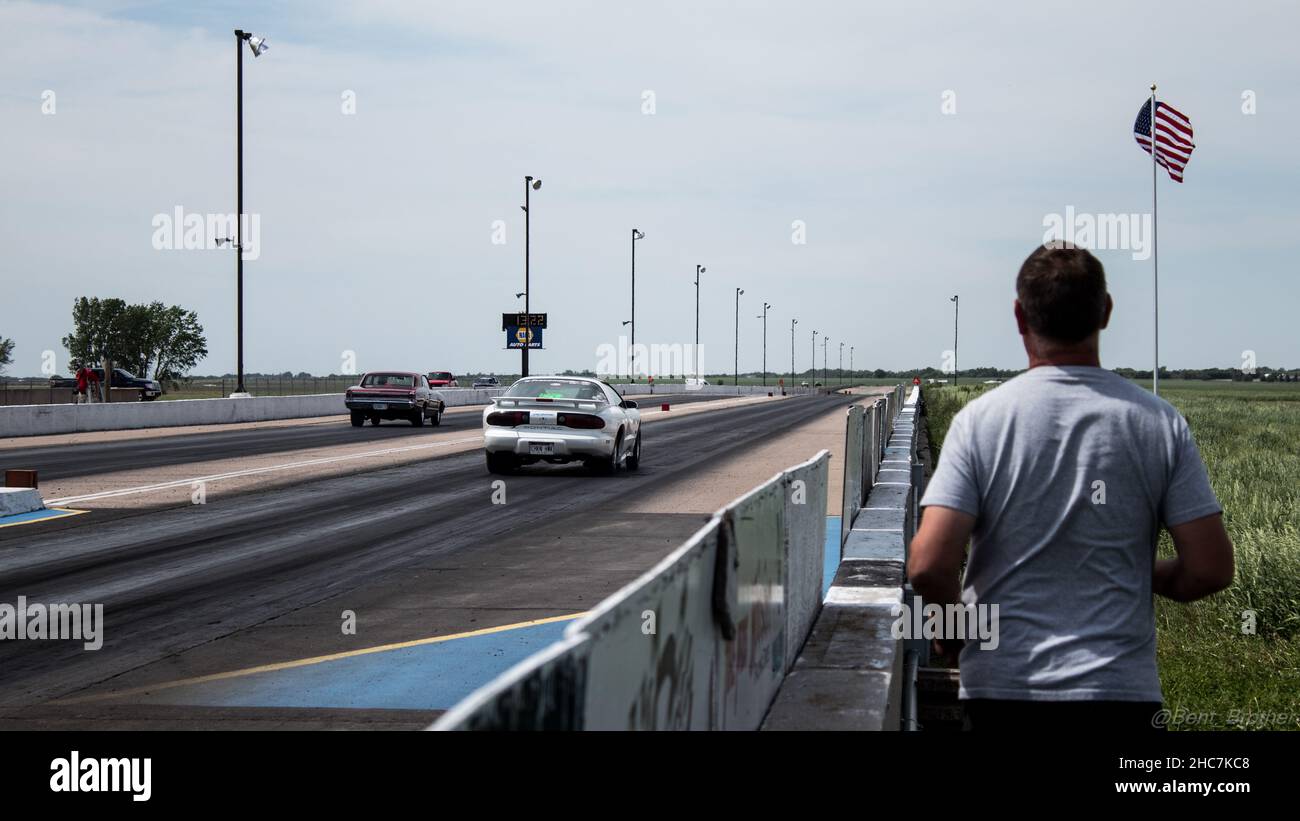 Morning at the drag race in Kearney, Nebraska with cars racing on the tracks and a man watching Stock Photo