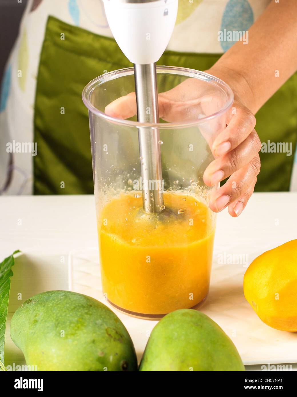A Woman Making Mango Juice (Smoothies) Using Hand Blender. Mango or Mangga Tropical Fruit Favorite Stock Photo
