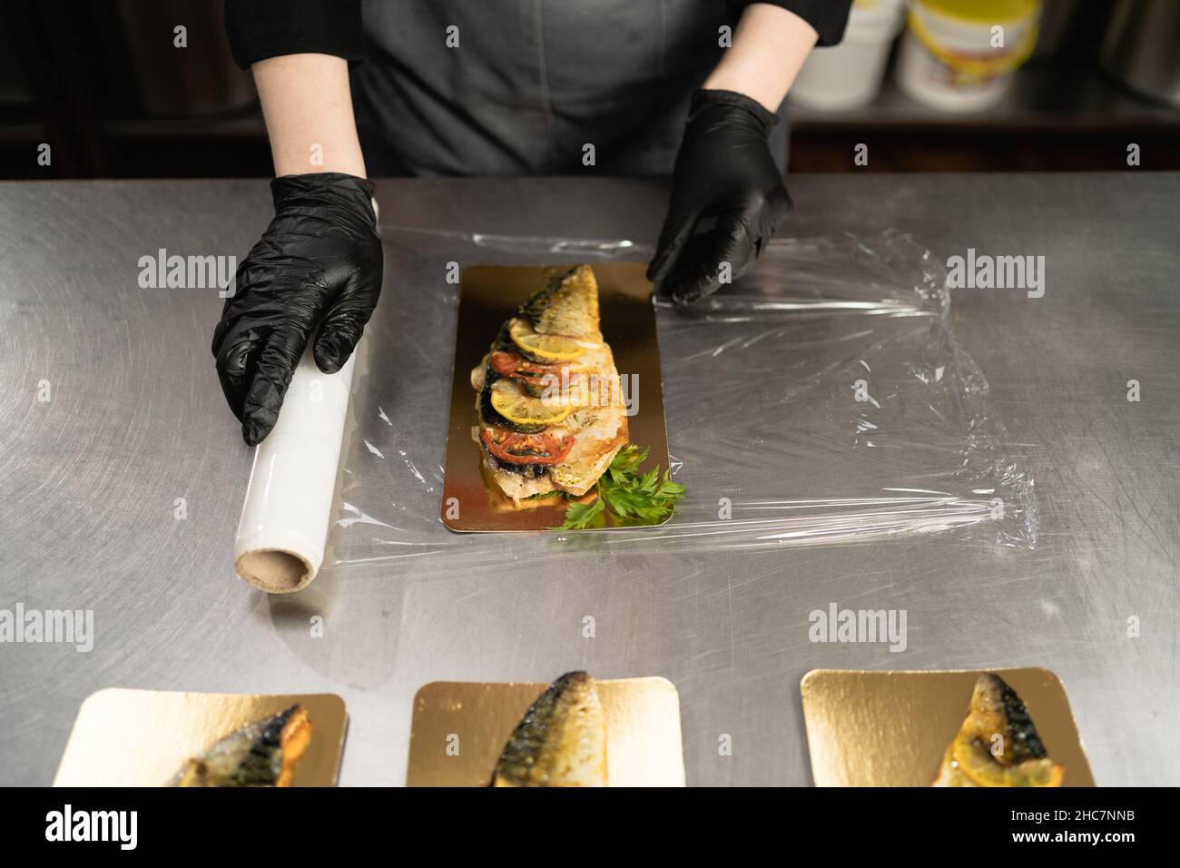 https://c8.alamy.com/comp/2HC7NNB/woman-using-cling-film-to-store-food-on-the-table-in-a-restaurant-in-the-kitchen-a-roll-of-transparent-plastic-cling-film-for-food-packaging-baked-2HC7NNB.jpg