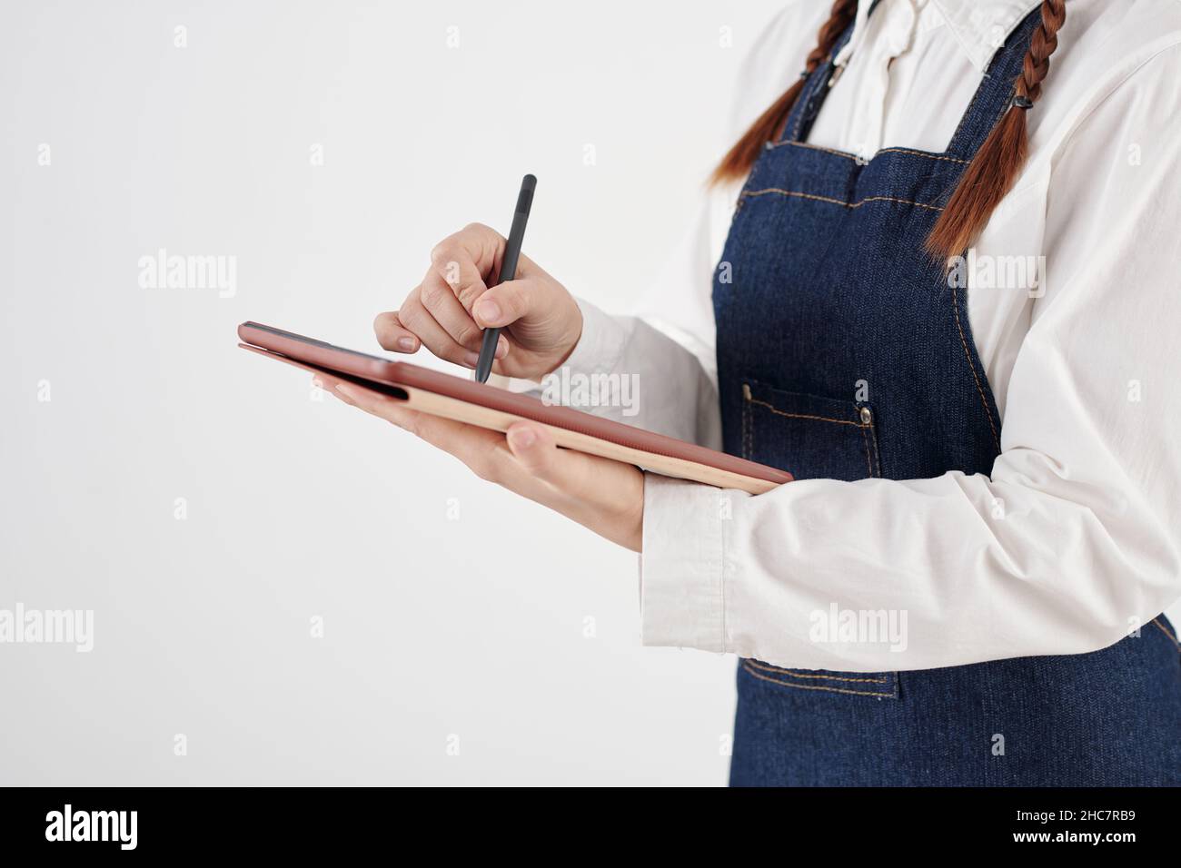 Cropped image of waitress in denim apron checking menu on tablet computer Stock Photo