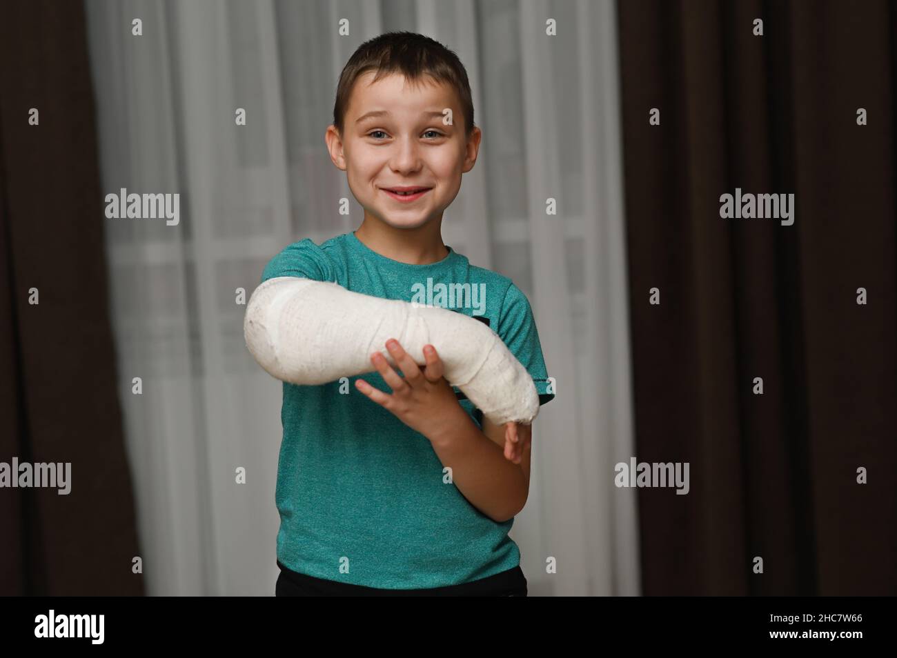 the boy has a cast on his arm and he's smiling. Stock Photo