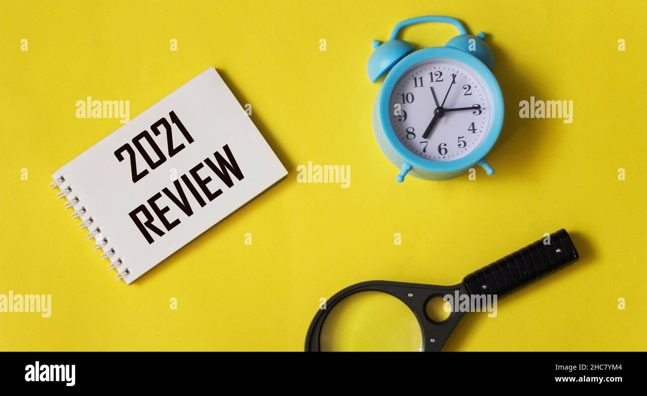 2021 review text on notepad with clock on yellow background, year end business concept Stock Photo