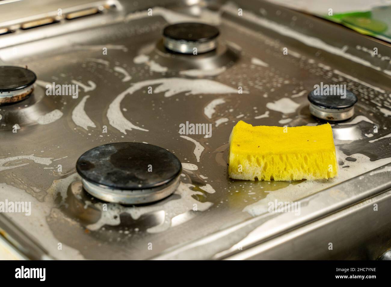 Yellow sponge for cleaning gas stove, cleaning the kitchen Stock Photo
