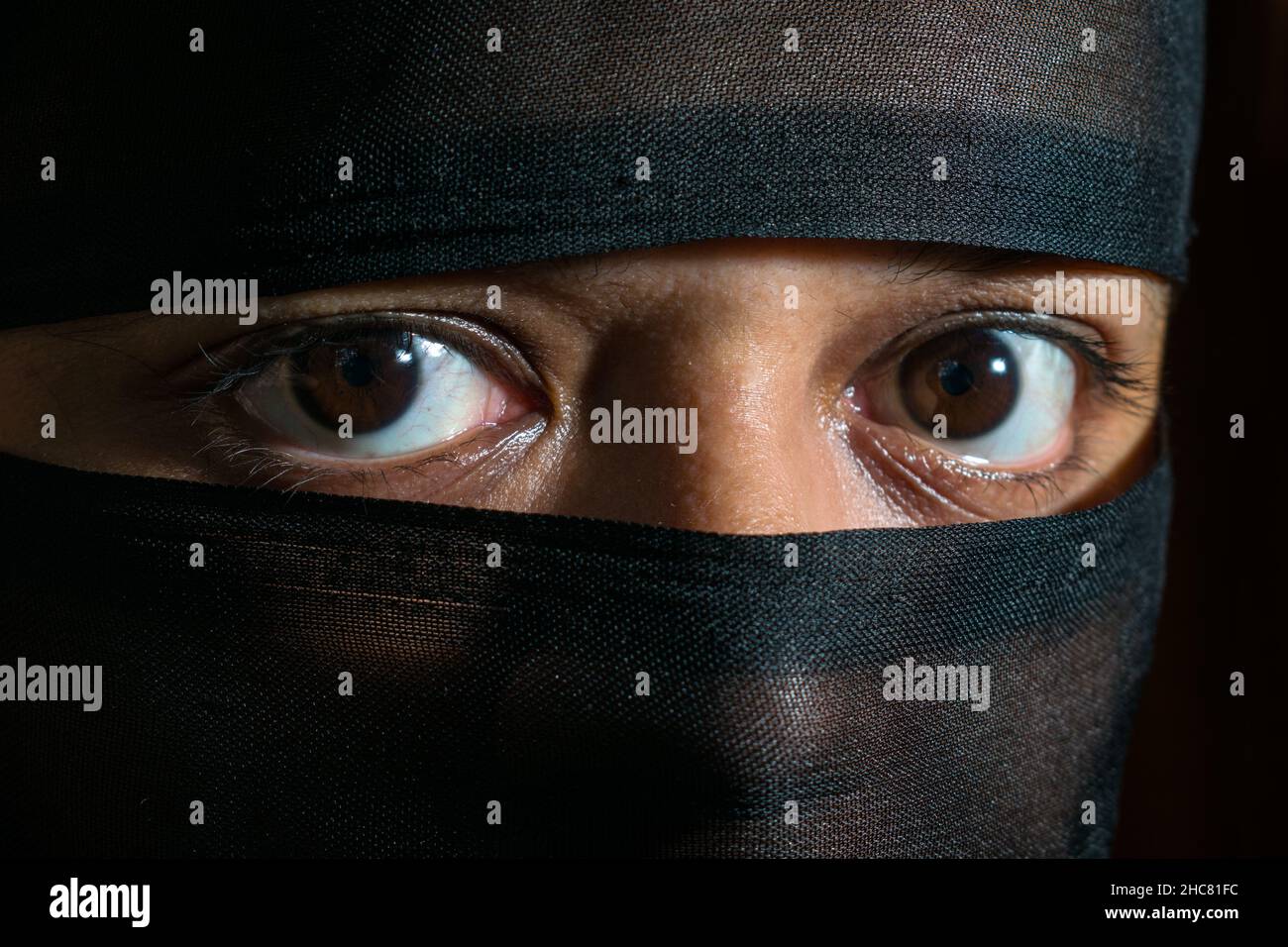 Close-up of the eyes with brown iris of a young woman wearing a black veil Stock Photo