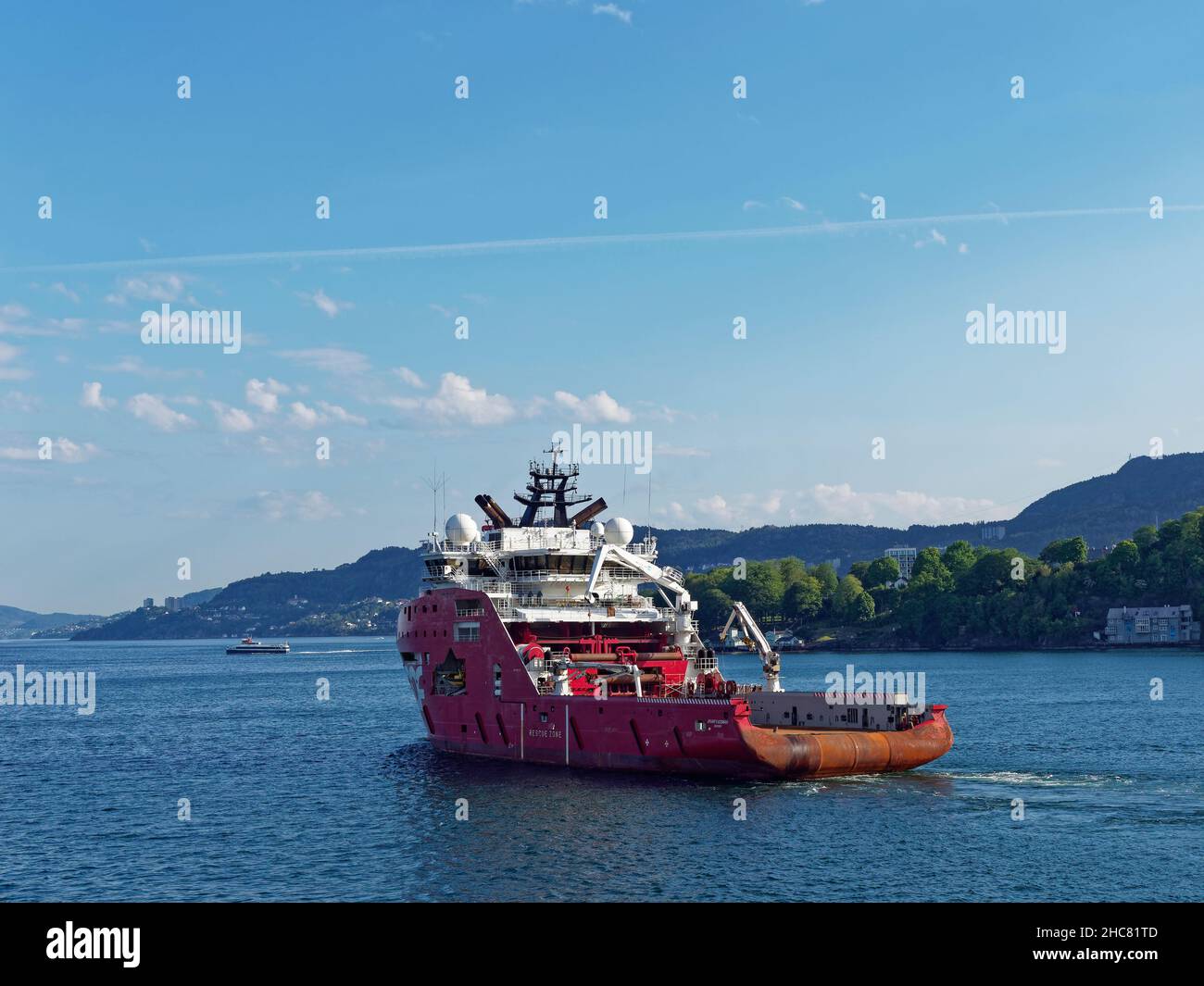 The Skandi Iceman, a Norwegian Registered Offshore Supply Vessel and Tug departing Bergen Harbour on a clear day in June Stock Photo