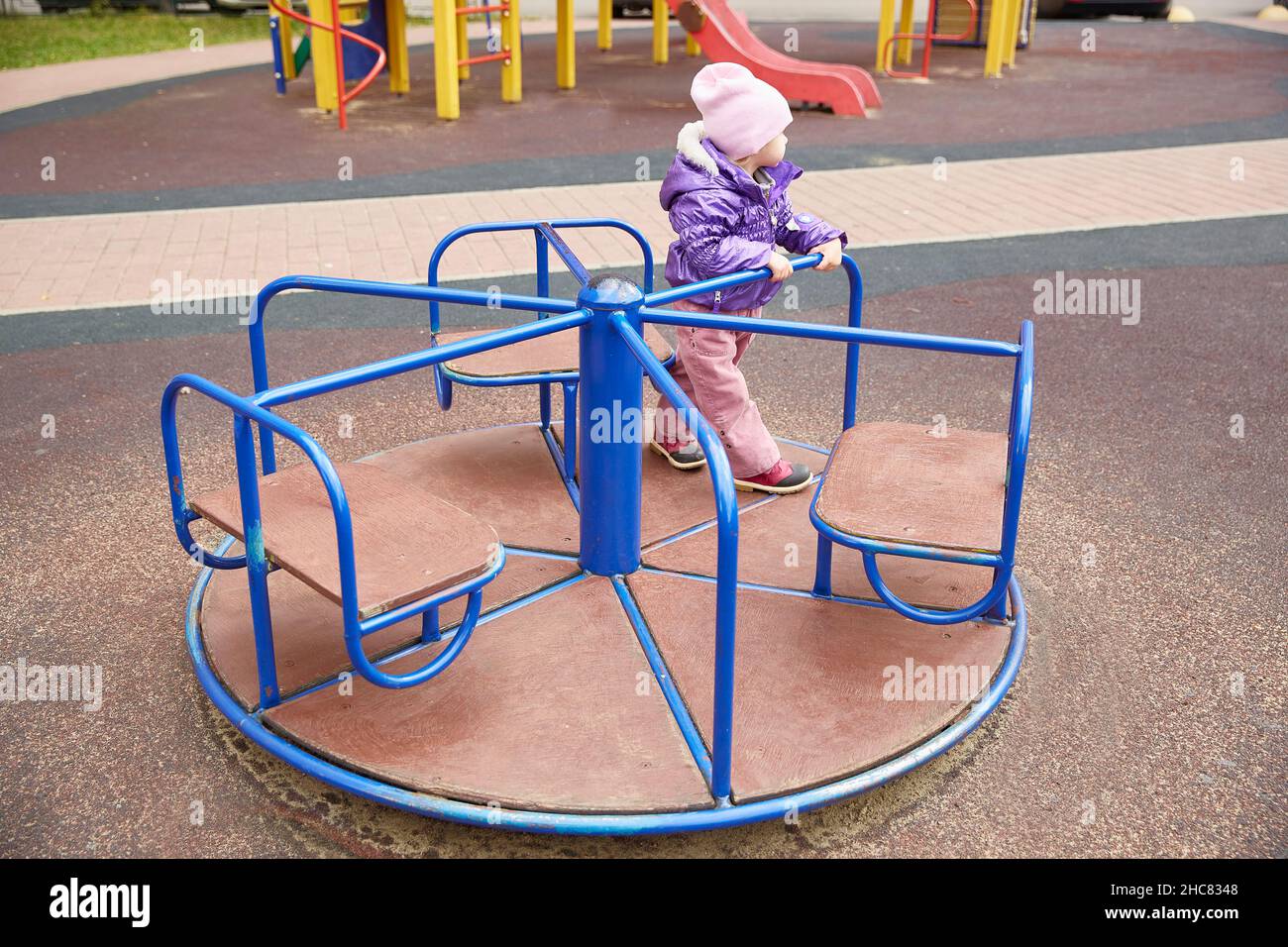 bored child on a carousel on a playground on an autumn sunny day Stock Photo