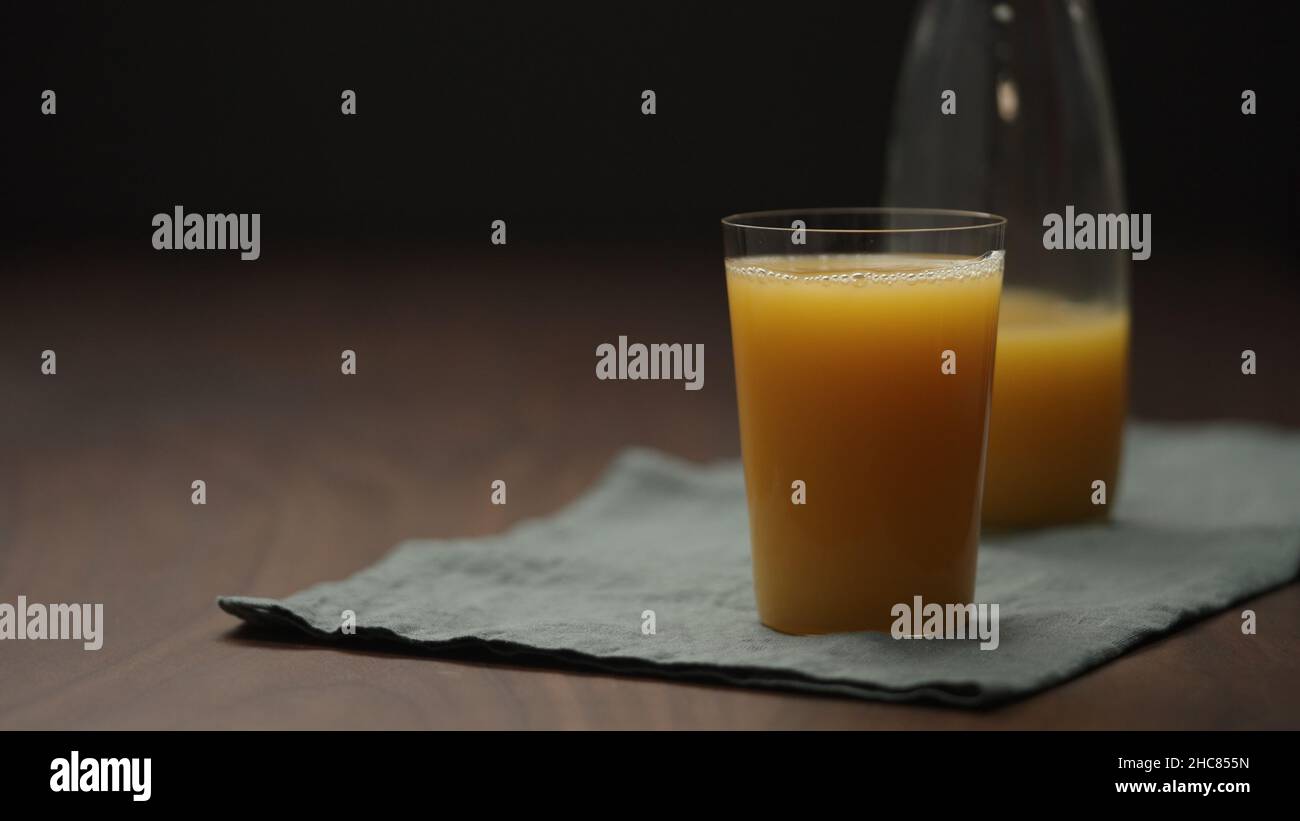 cold pressed organic orange juice tumbler glass on wood table, wide