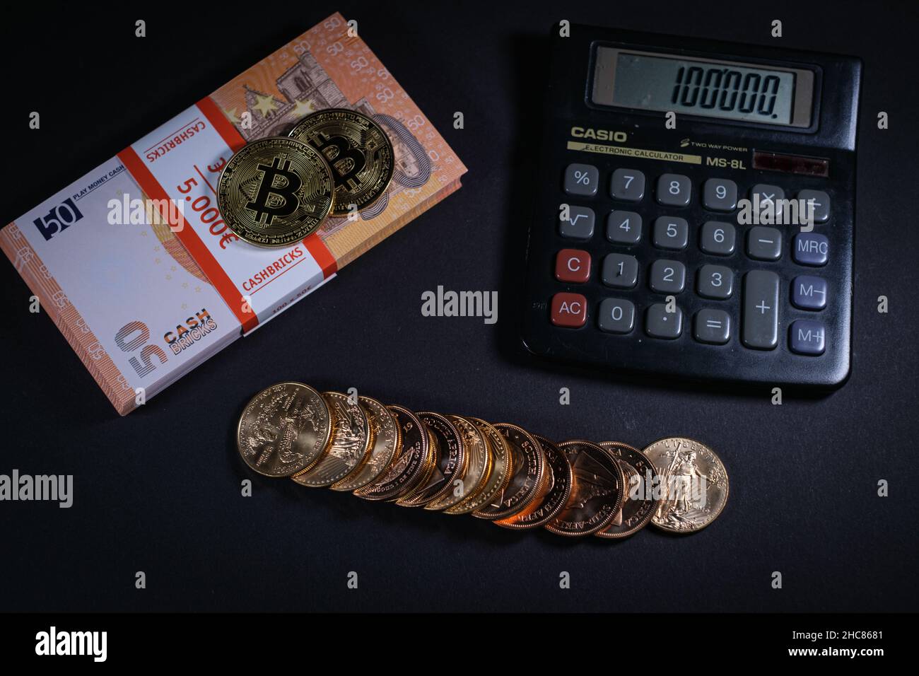 gold coins are lying next to a stack of euro banknotes, bitcoin and euín  calculator Stock Photo - Alamy