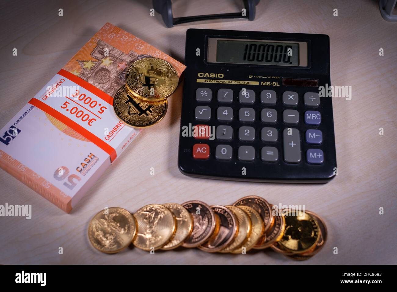 gold coins are lying next to a stack of dollar banknotes, bitcoin and a  calculator Stock Photo - Alamy