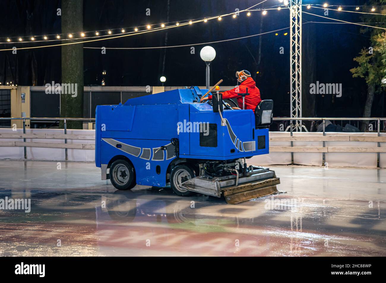 A stadium worker cleans an ice rink on a blue modern ice cleaning