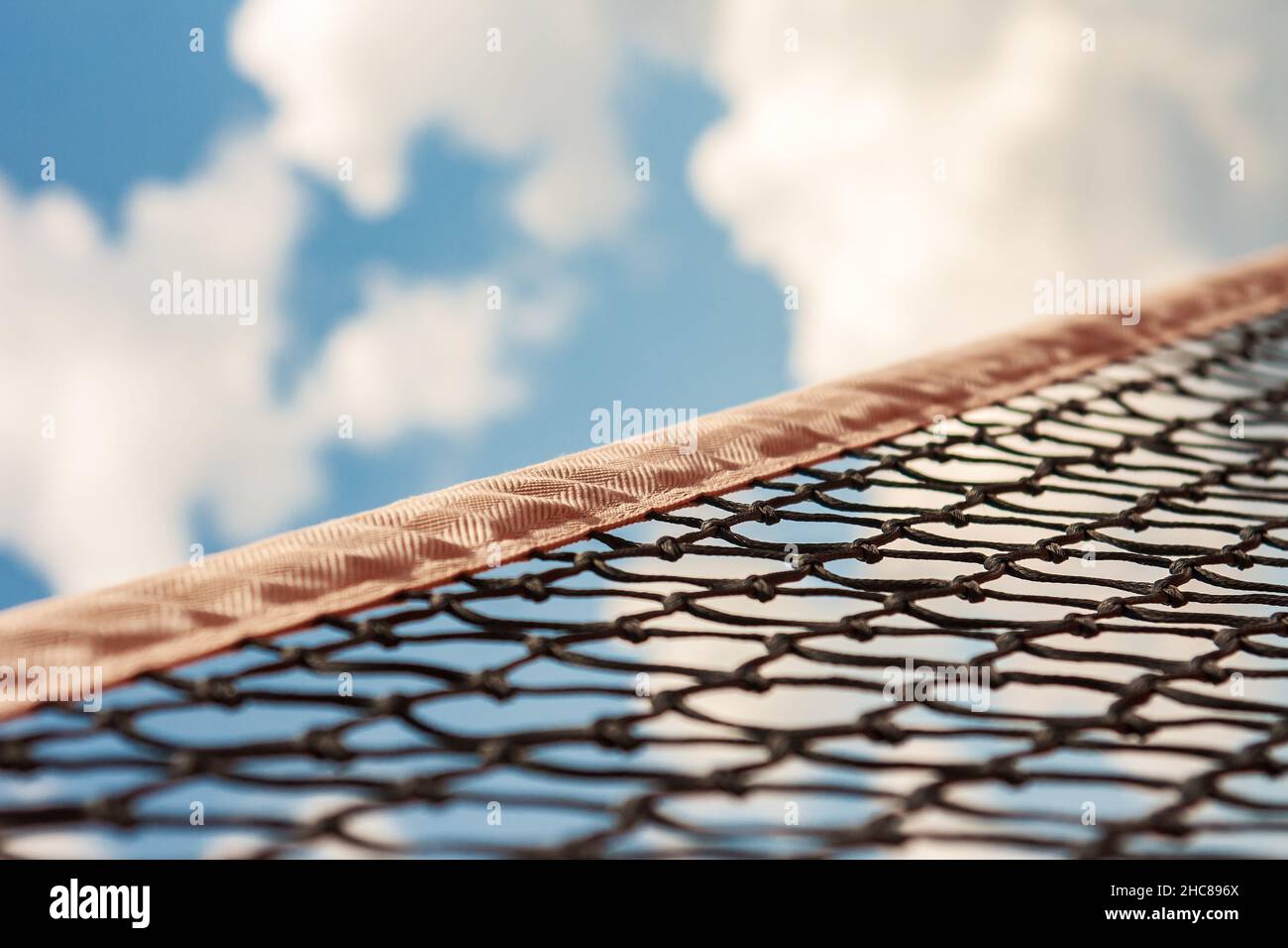 Тennis sport net against the bright blue sky with clouds. Stock Photo