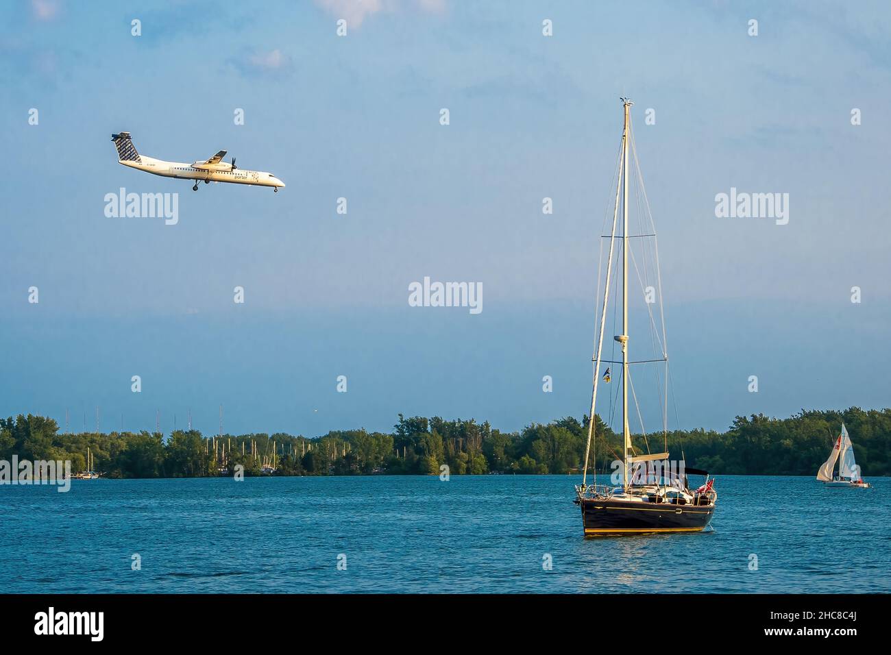 Toronto, Canada - July 1, 2015: Propeller plane landing in Porter Airport in Toronto during Canada's Day.The plane is landing over the lake. A small s Stock Photo