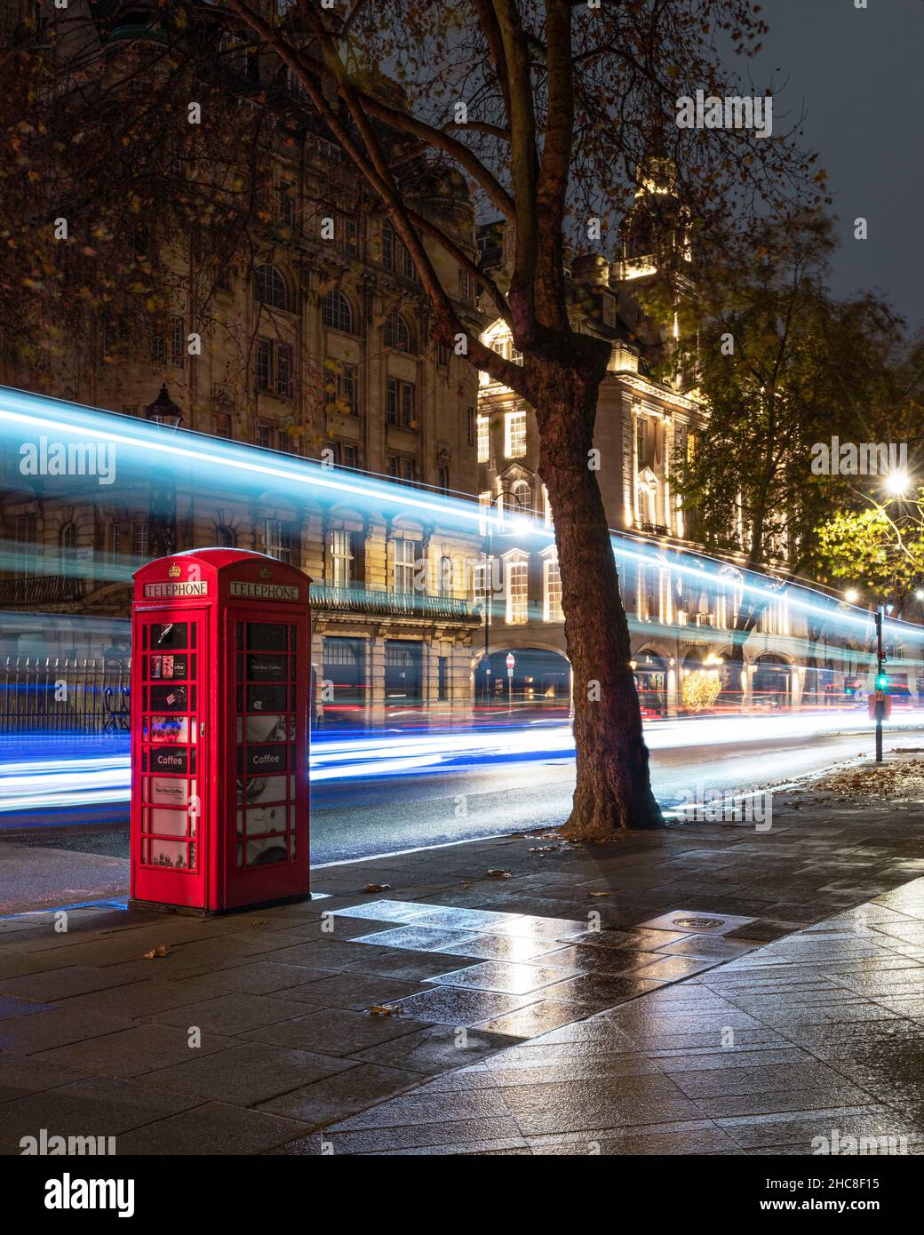 Red phone booth with bus trails in London street Stock Photo