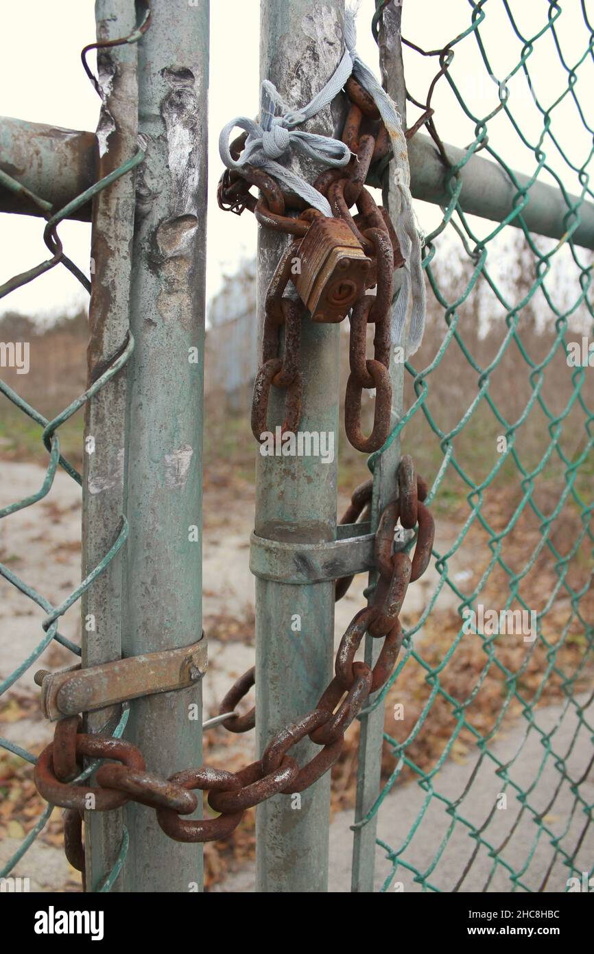 Old rusted lock and chain hold a chain link fence gate closed as a form of security Stock Photo